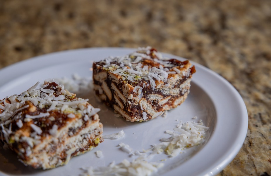 Two slices of layered biscuit dessert topped with coconut on a plate.