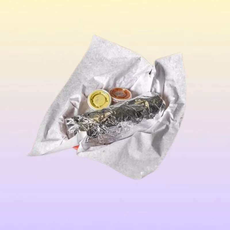 Foil-wrapped burrito and two sauce cups in white paper.