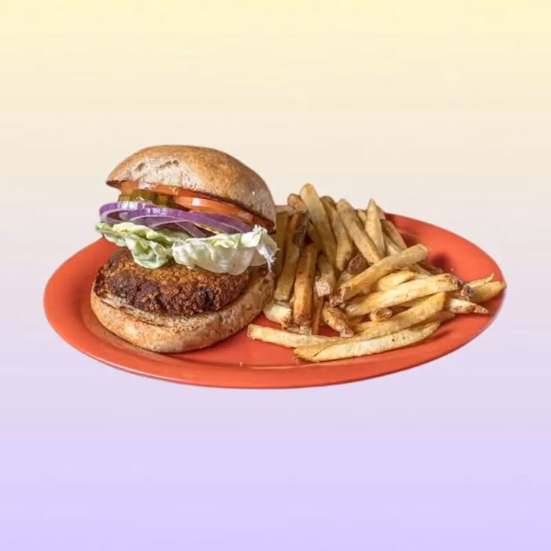 Burger with veggie patty, lettuce, onion, tomato, pickles, and fries.