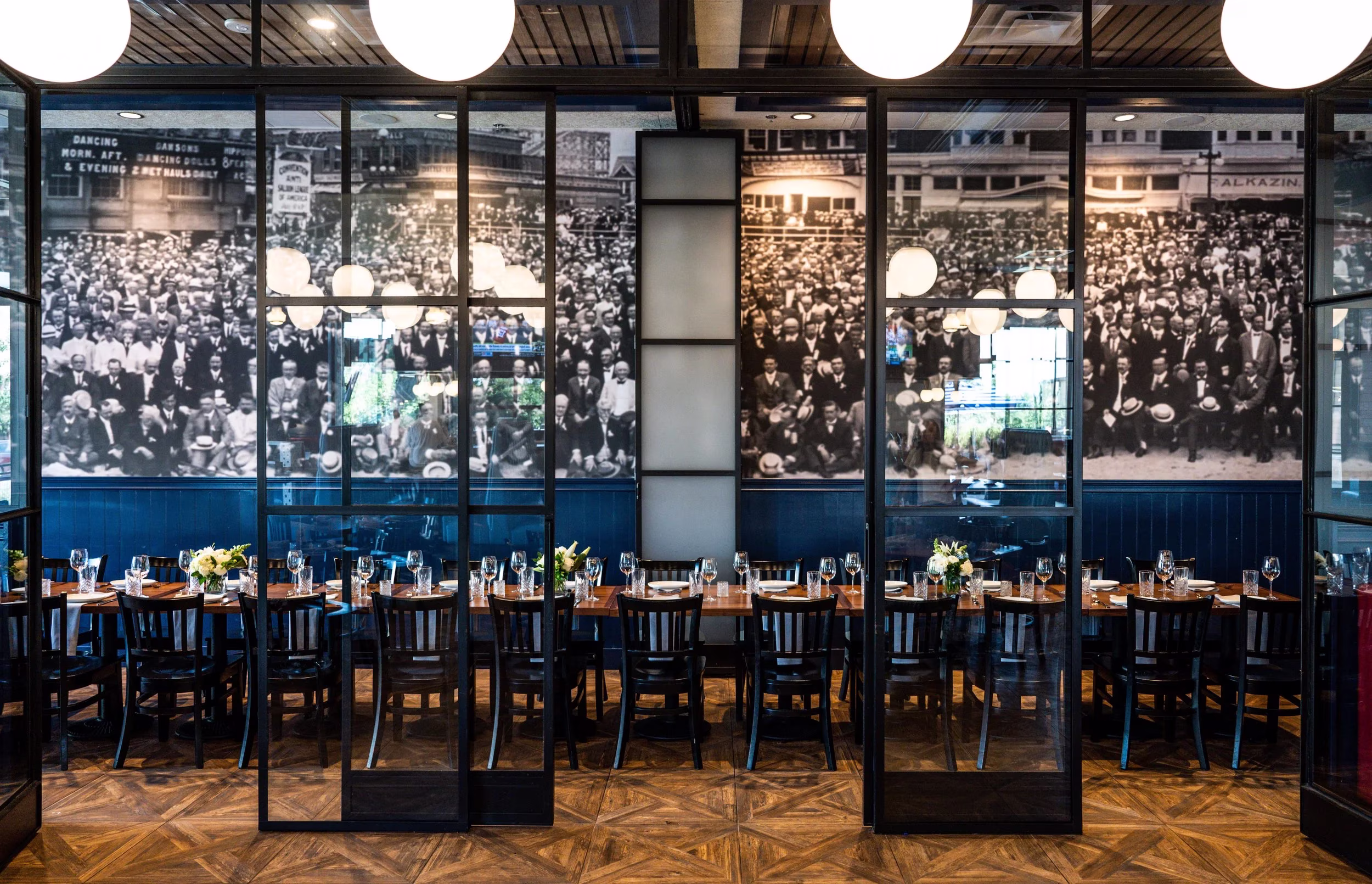 Restaurant with historical crowd photos, wooden tables, and glass dividers.