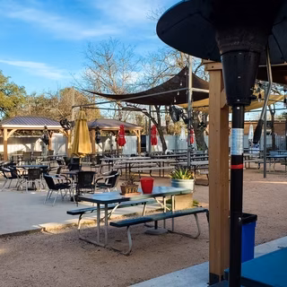 Outdoor restaurant patio with tables, chairs, sun shades, and heater.
