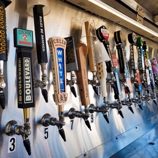 A long row of various beer taps with brand handles.