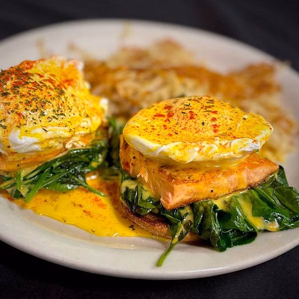 Two salmon eggs Benedict with spinach, hollandaise, and hash browns.