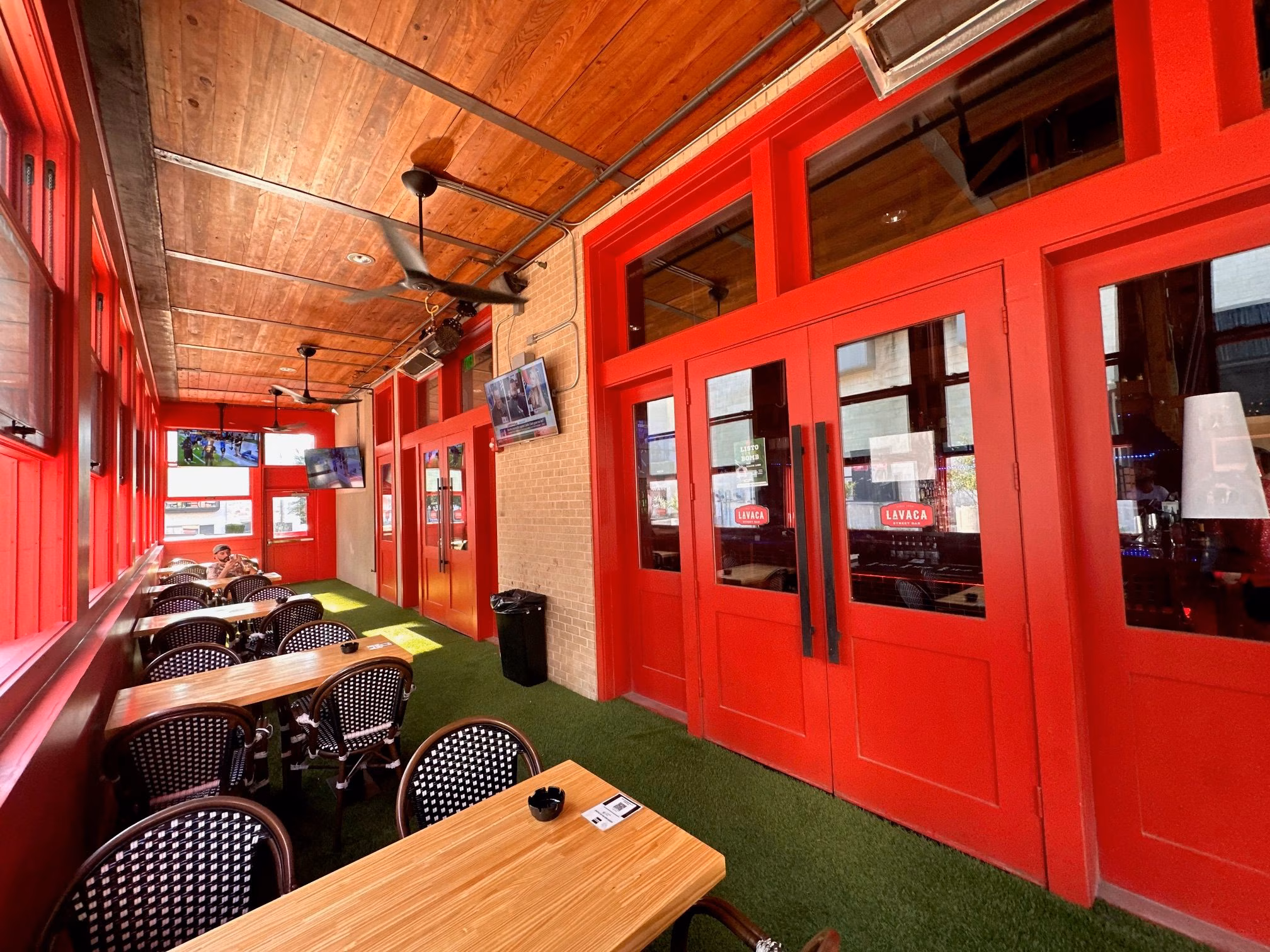 Inside Lavaca Street Bar with red walls, wood ceiling, and green turf.