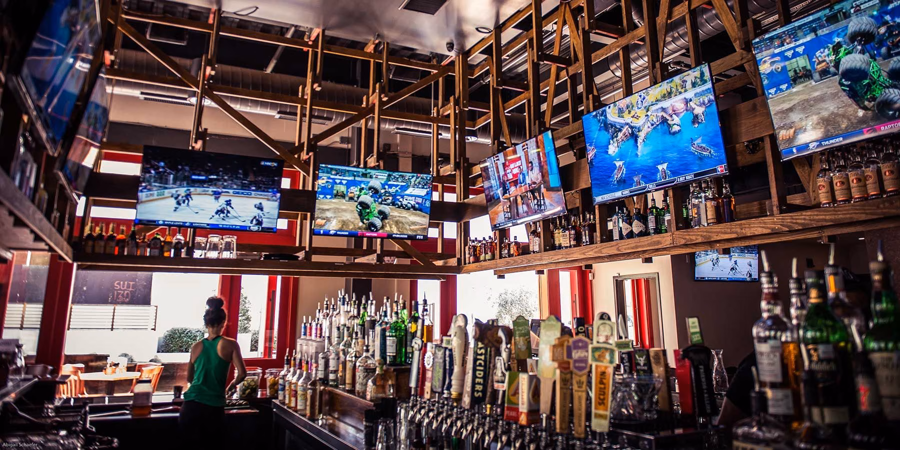 Numerous televisions showing various sports above a well-stocked bar.