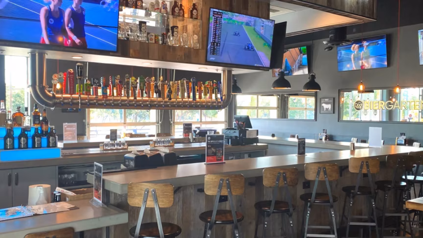 Interior of a bar with many beer taps and multiple televisions.