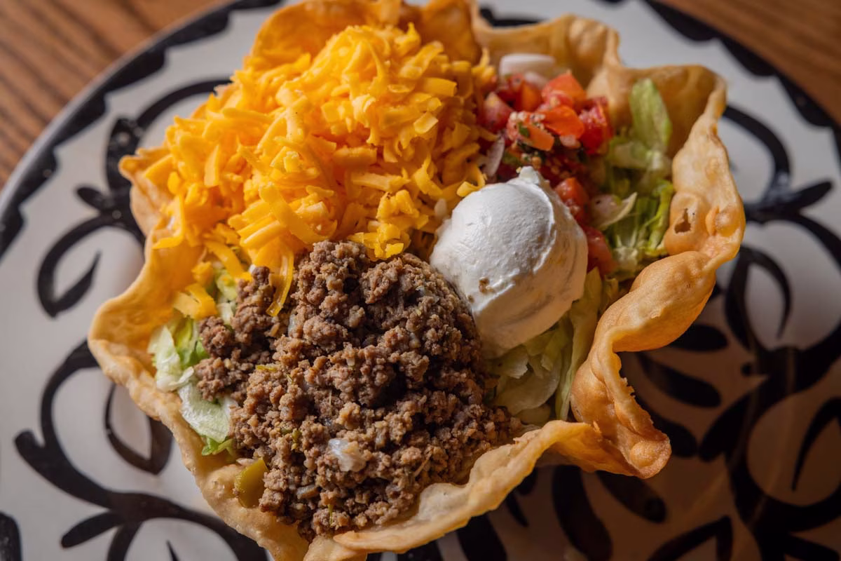 Taco salad with ground beef, cheese, lettuce, tomato, and sour cream.