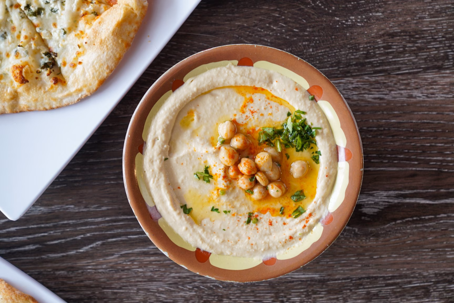 Hummus with chickpeas, olive oil, and herbs, alongside flatbread.