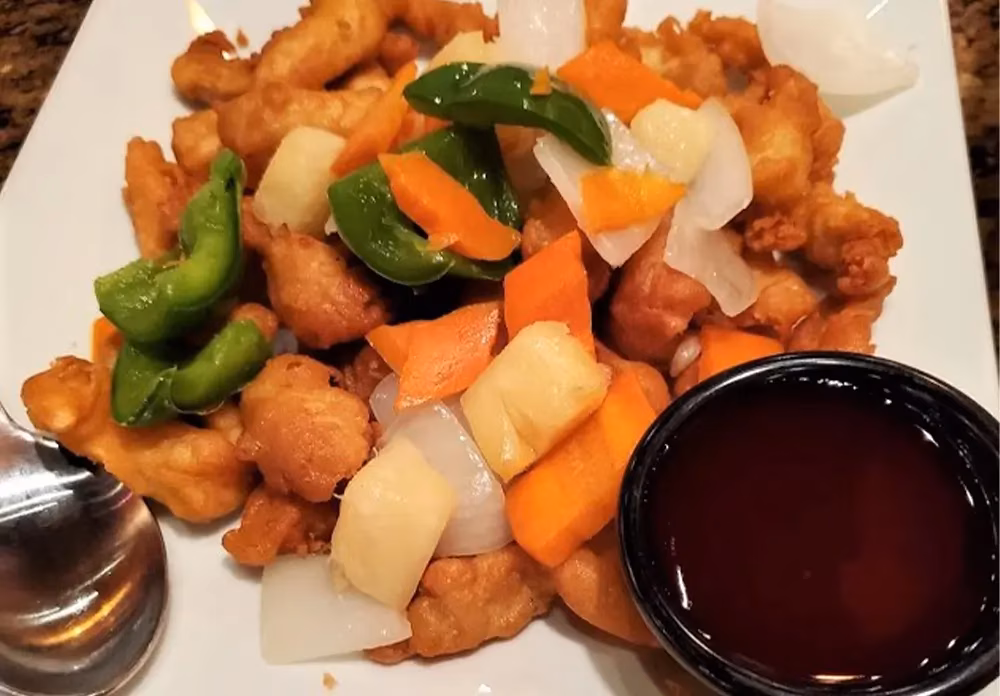 Fried chicken pieces, bell peppers, carrots, pineapple, onions, and sauce.