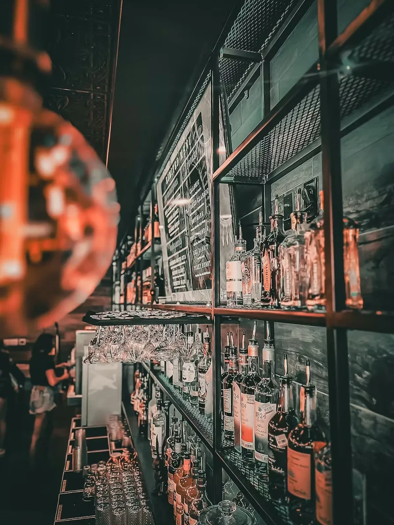 Moody, well-stocked bar interior with liquor bottles and clean glasses.