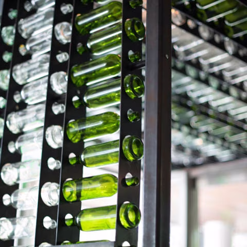 Decorative wall of cut clear and green glass bottles.