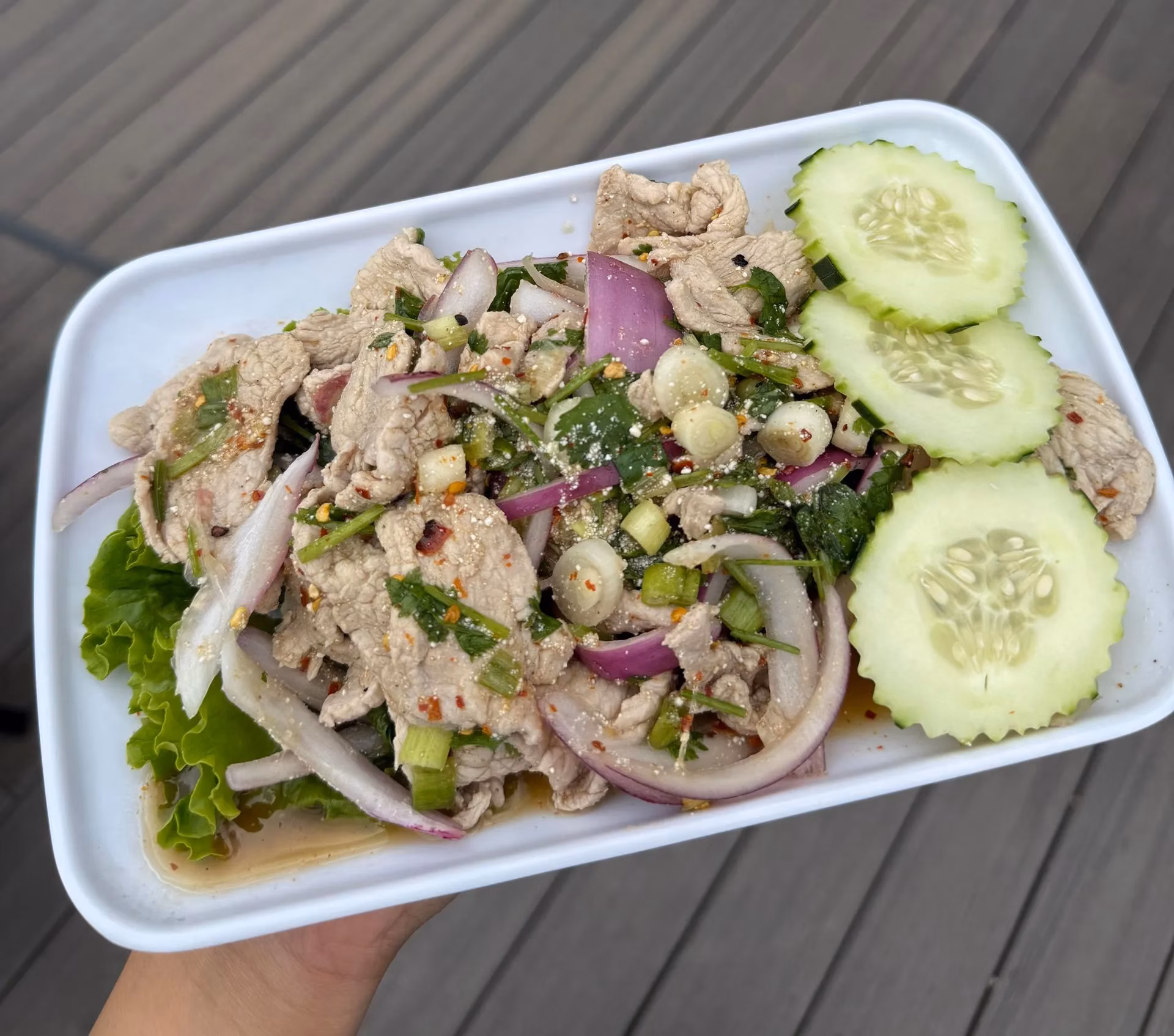 Thai pork salad with red onion, cilantro, and cucumber.