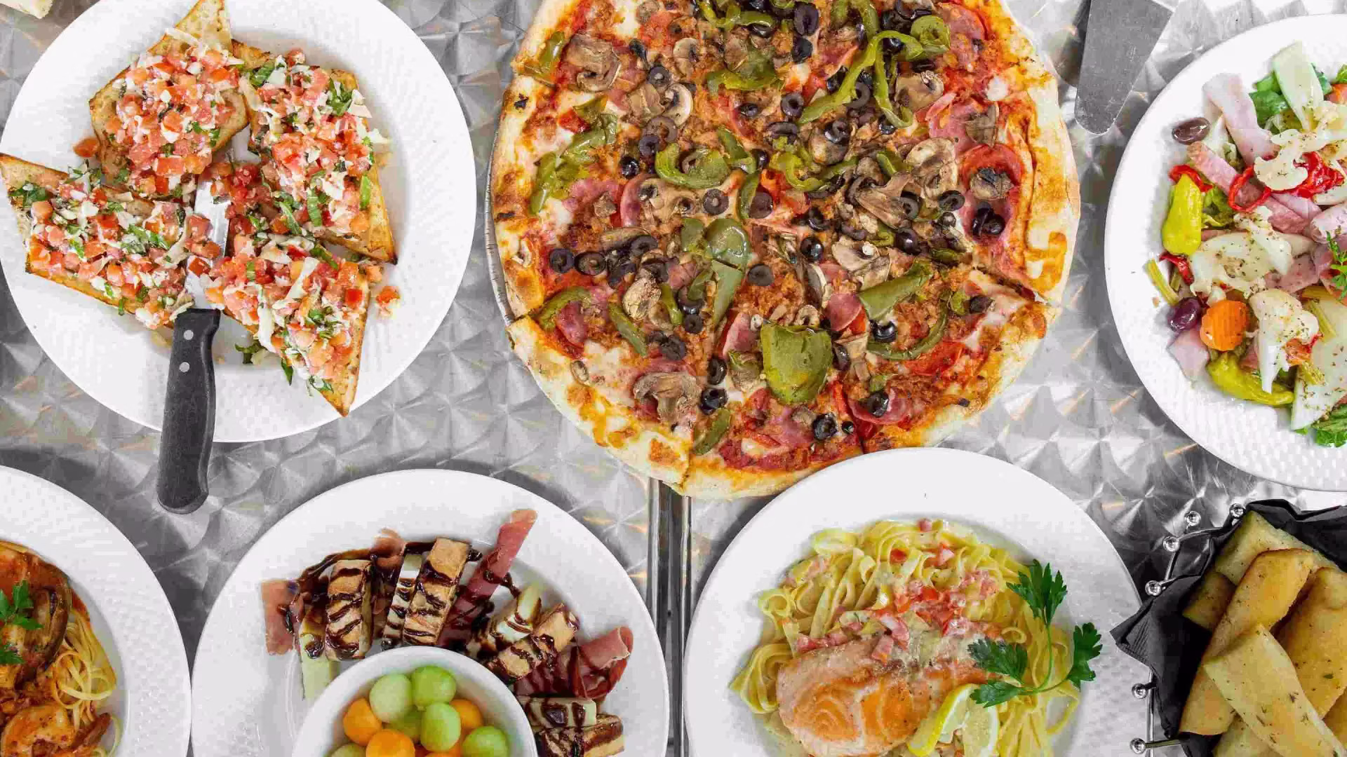 Assortment of Italian cuisine including pizza, pasta, bruschetta, and salad.