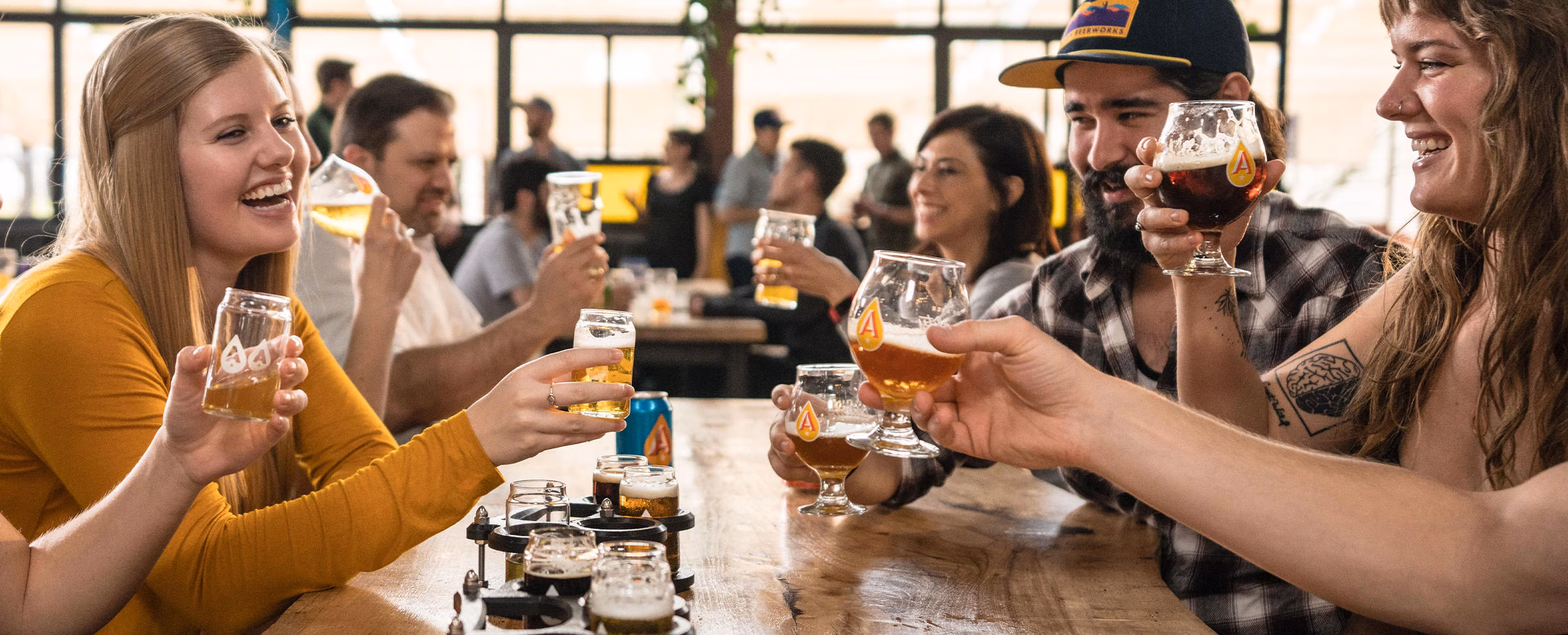 People clink beer glasses, including a tasting flight.