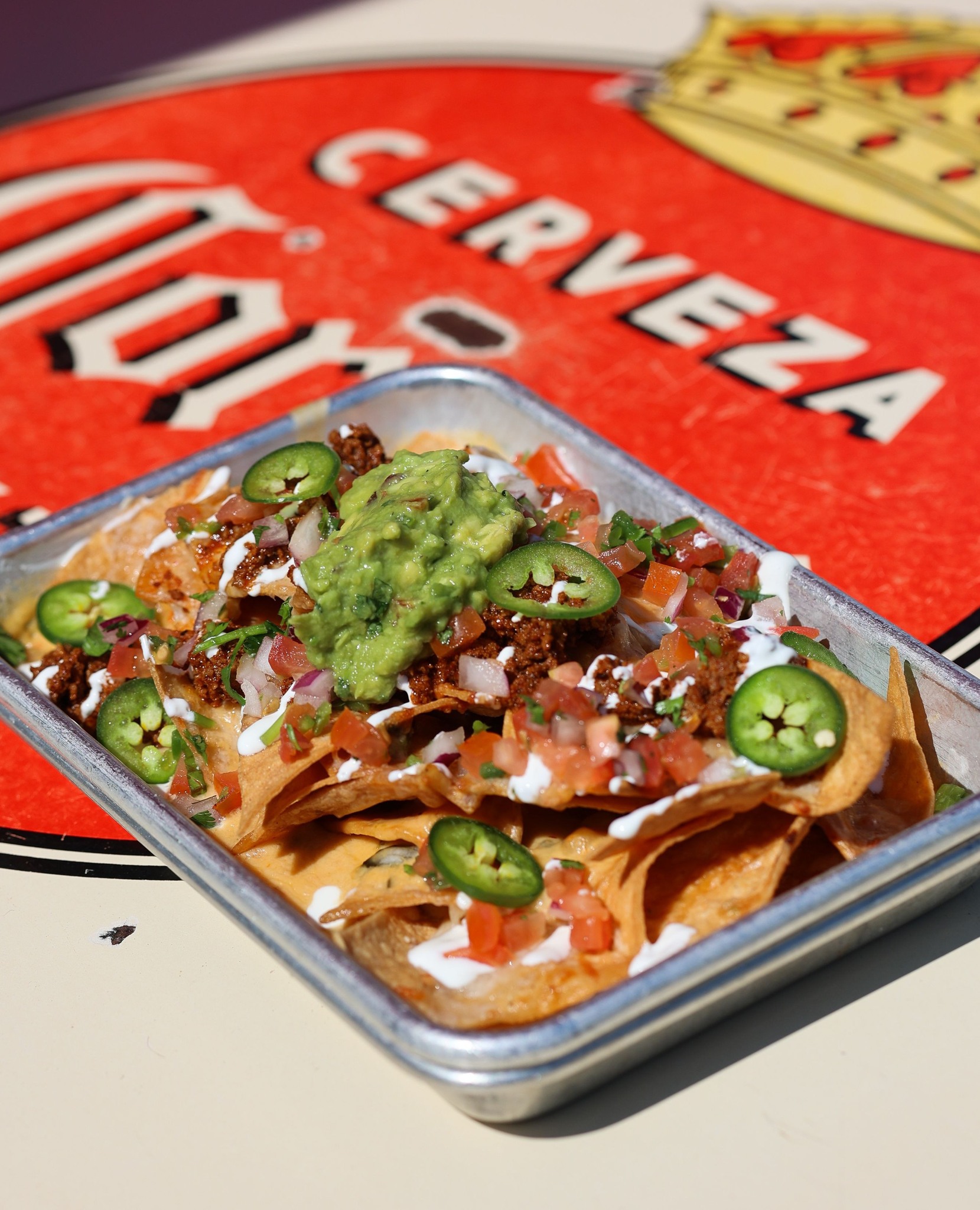 Nachos with guacamole, meat, pico de gallo, and jalapeños.