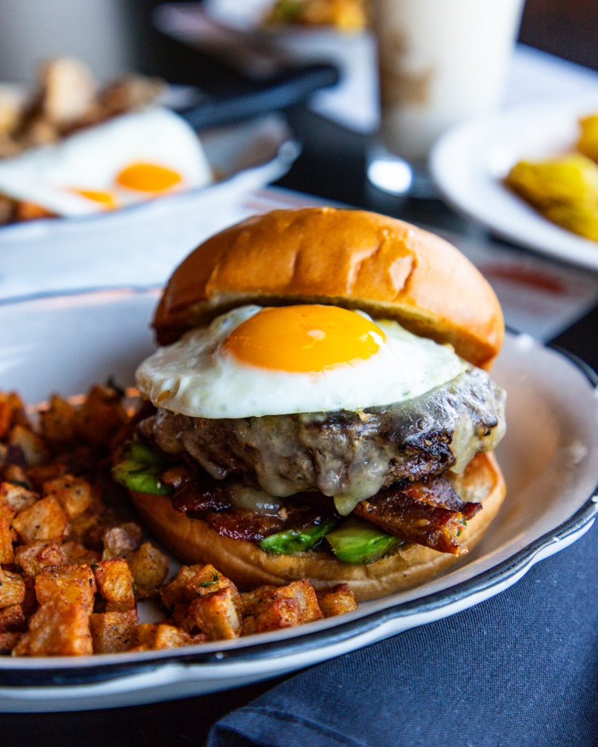 Breakfast burger with fried egg, cheese, bacon, avocado, and hash browns.