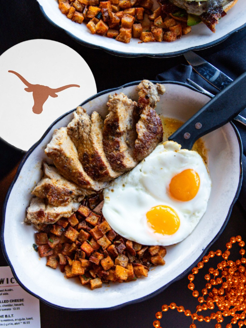 Plate of sliced meat, fried eggs, roasted potatoes, and Longhorn coaster.