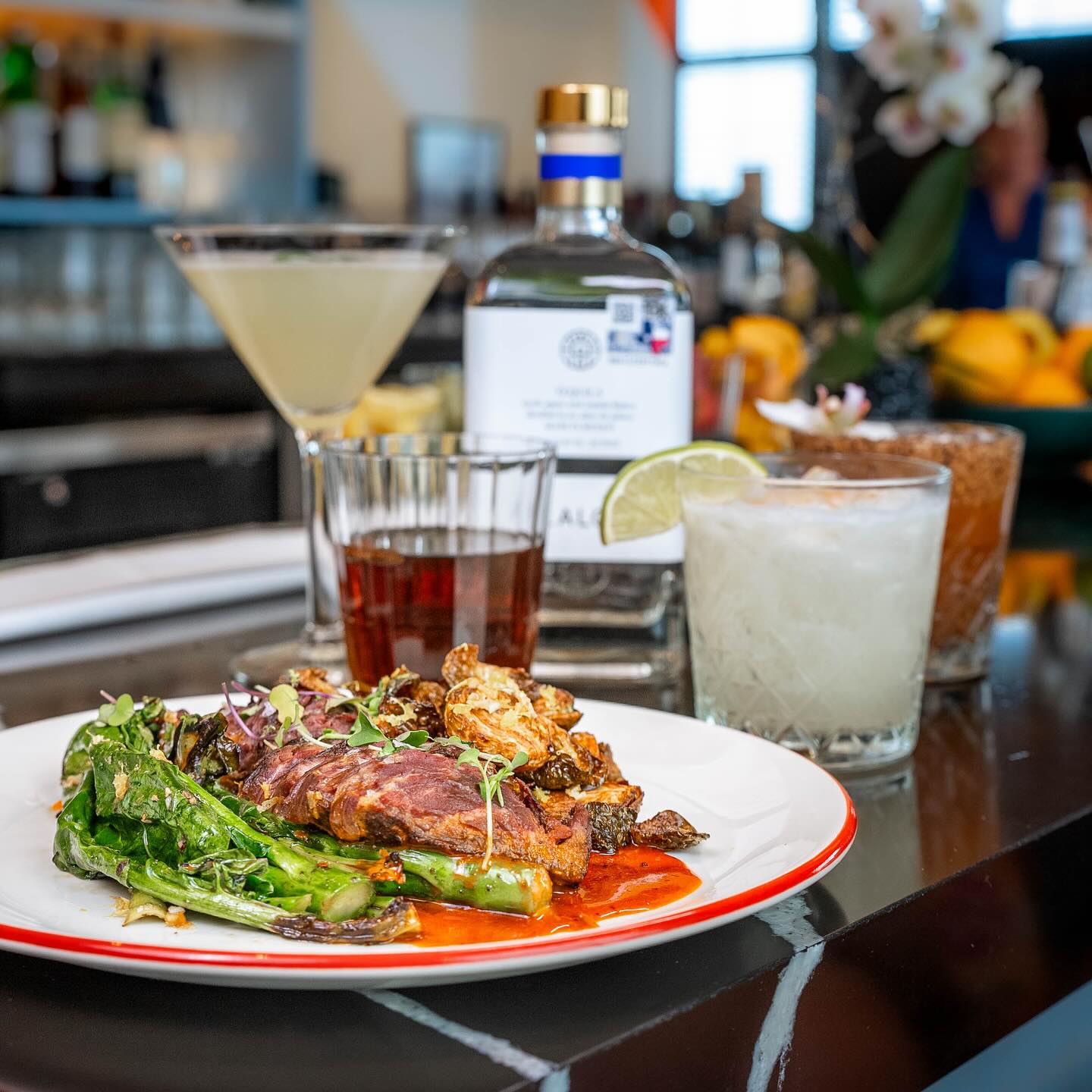 Four drinks and a spirit bottle alongside a food plate.