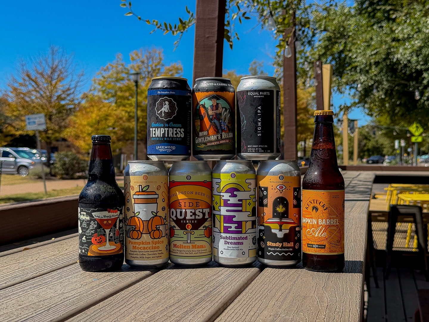 Collection of pumpkin-themed and various craft beers on a wooden table.