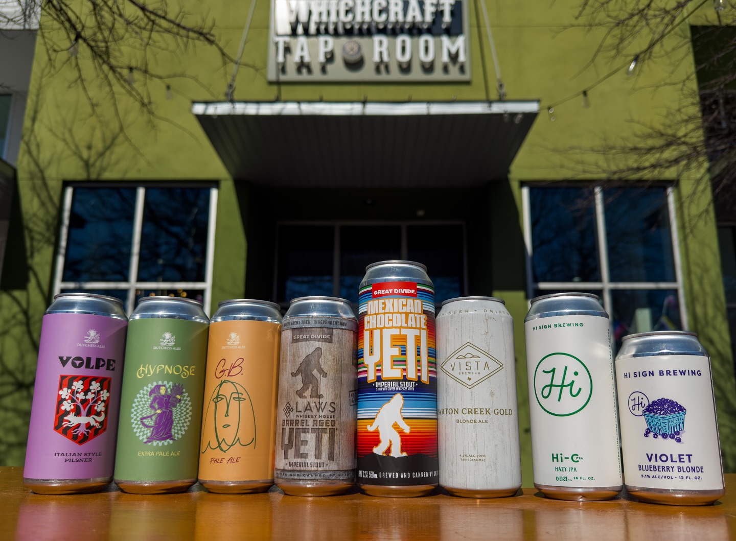Eight different beer cans in front of Whichcraft Tap Room.