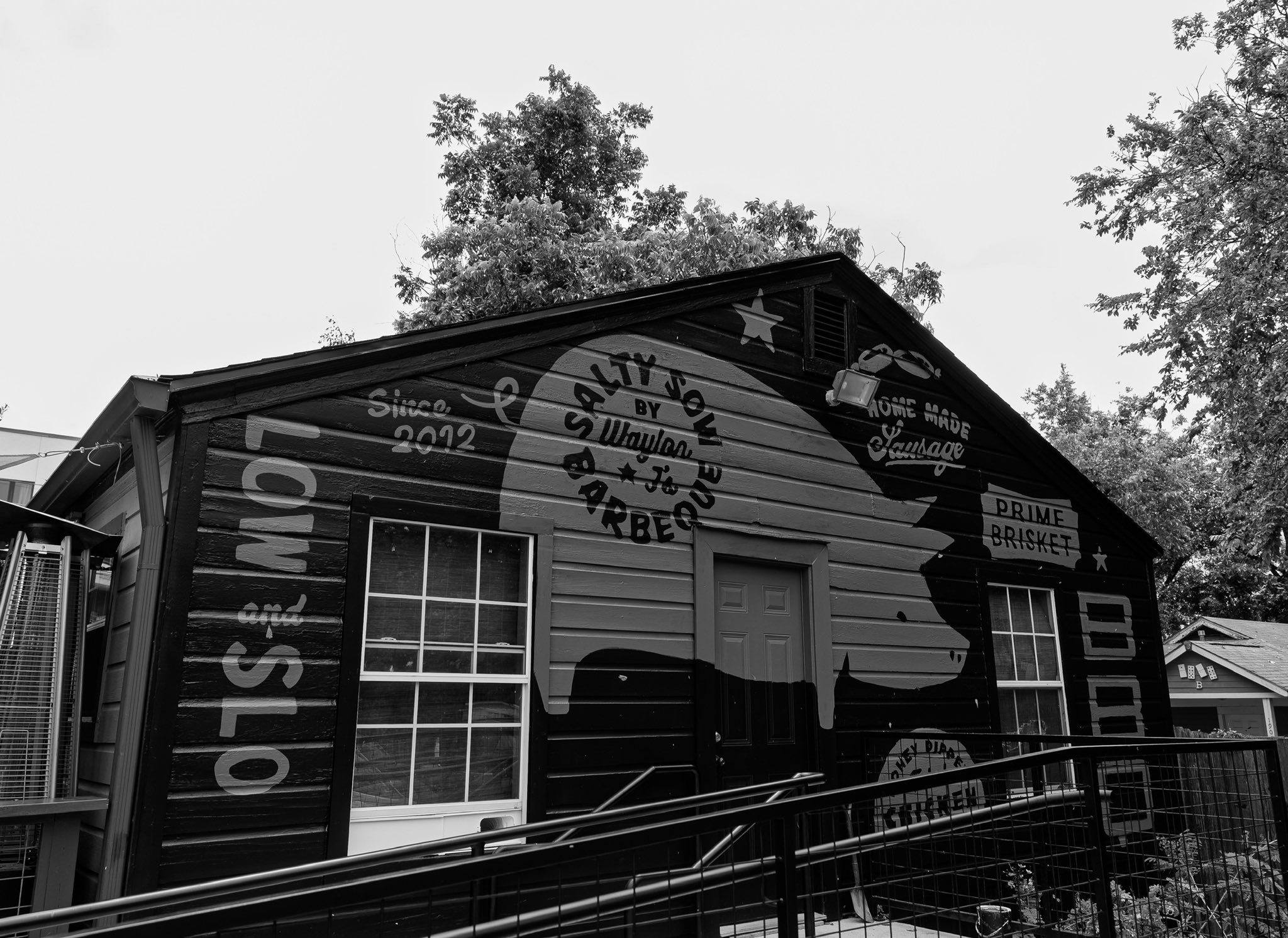 Black and white image of a wooden building with Salty Sow Barbecue signs.