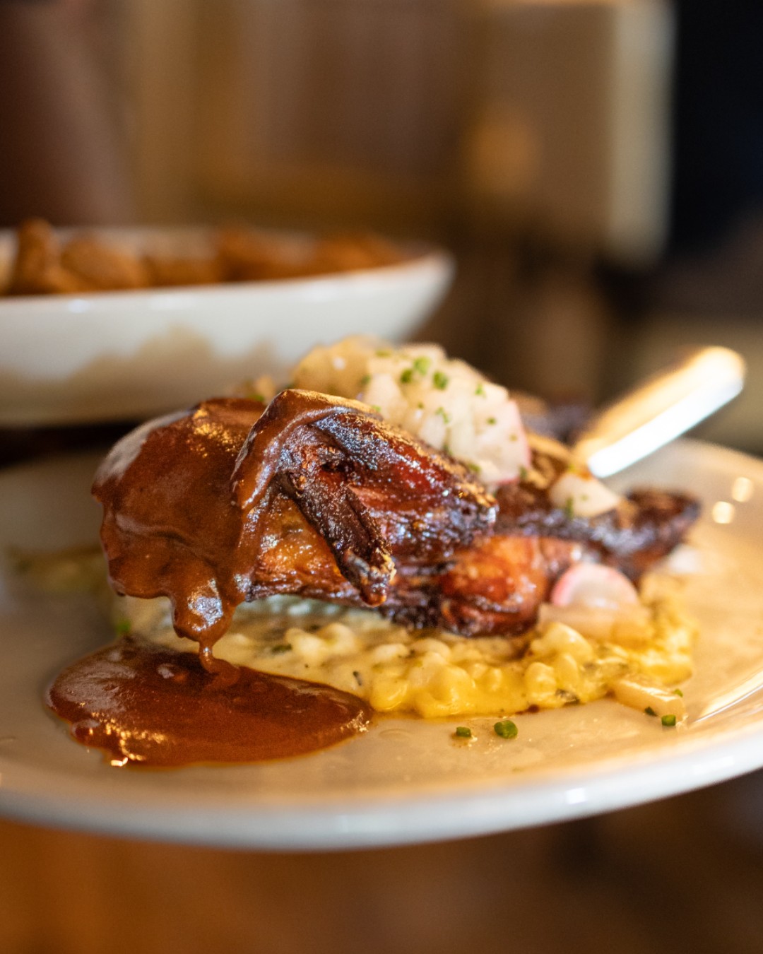 Roasted meat with dark sauce, mashed potatoes, and corn on a plate.