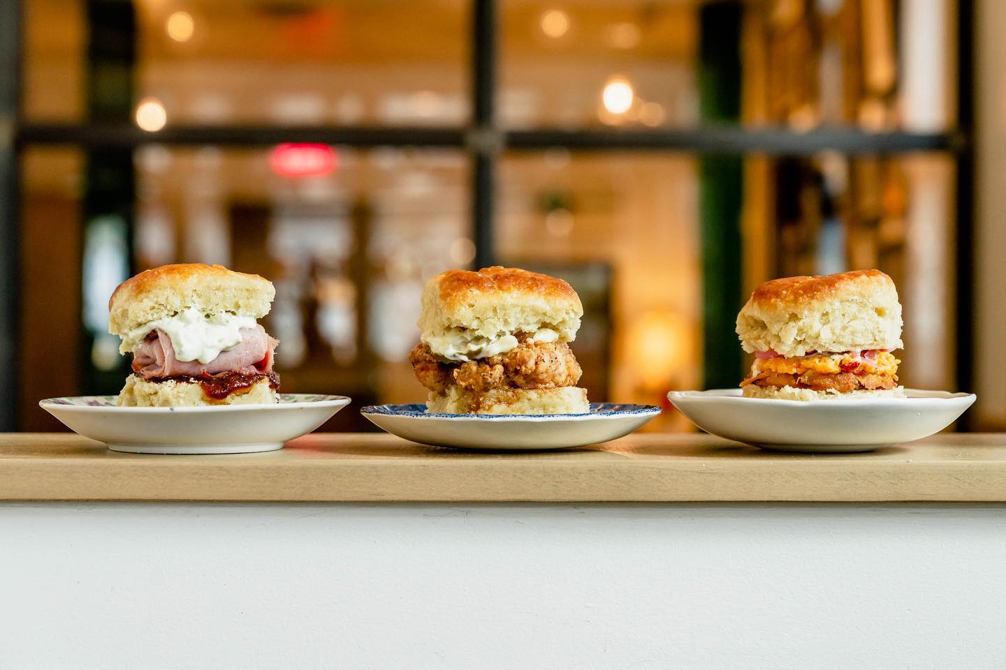 Three different biscuit sandwiches on small white plates.