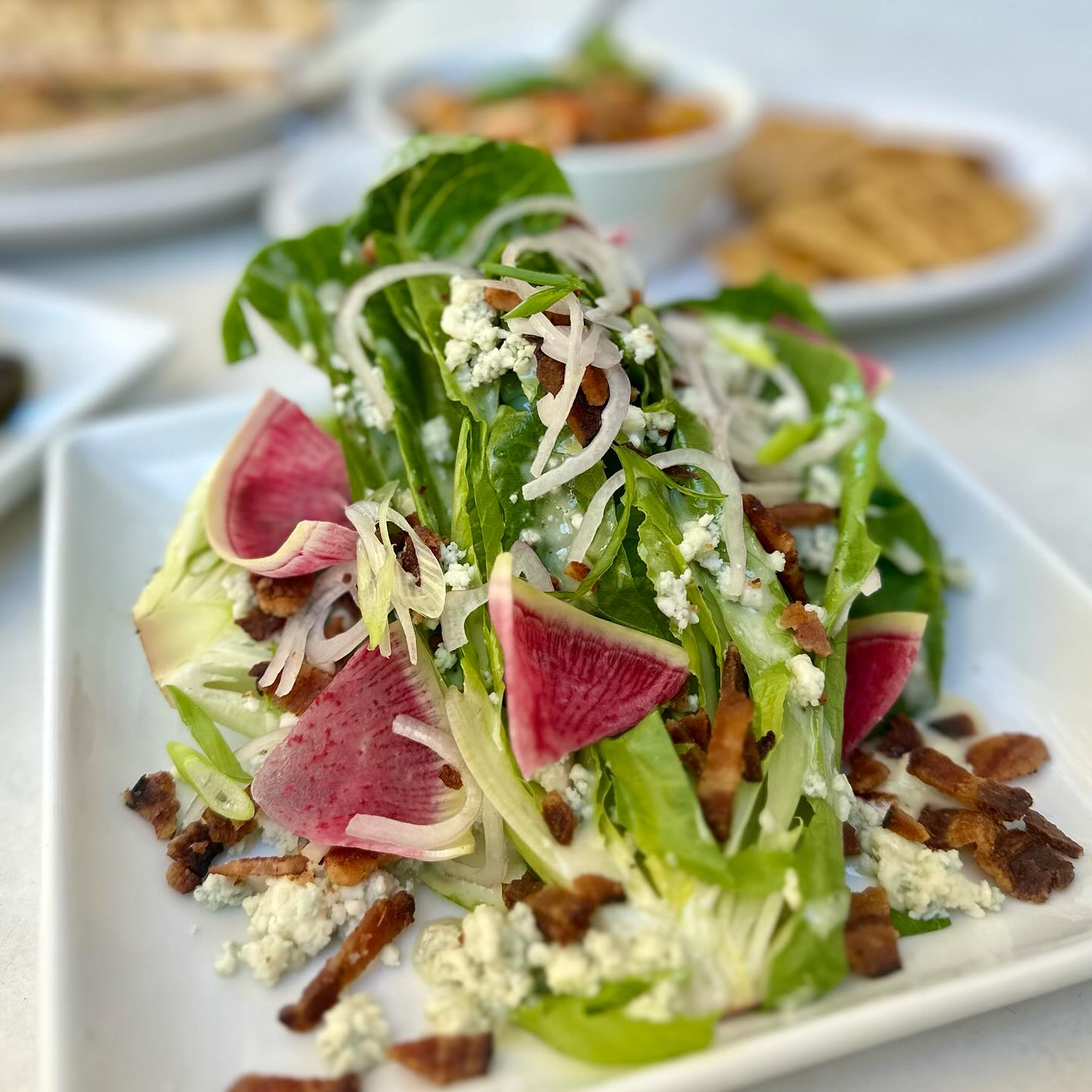 Salad with lettuce, blue cheese, bacon, radish, and sliced onions.