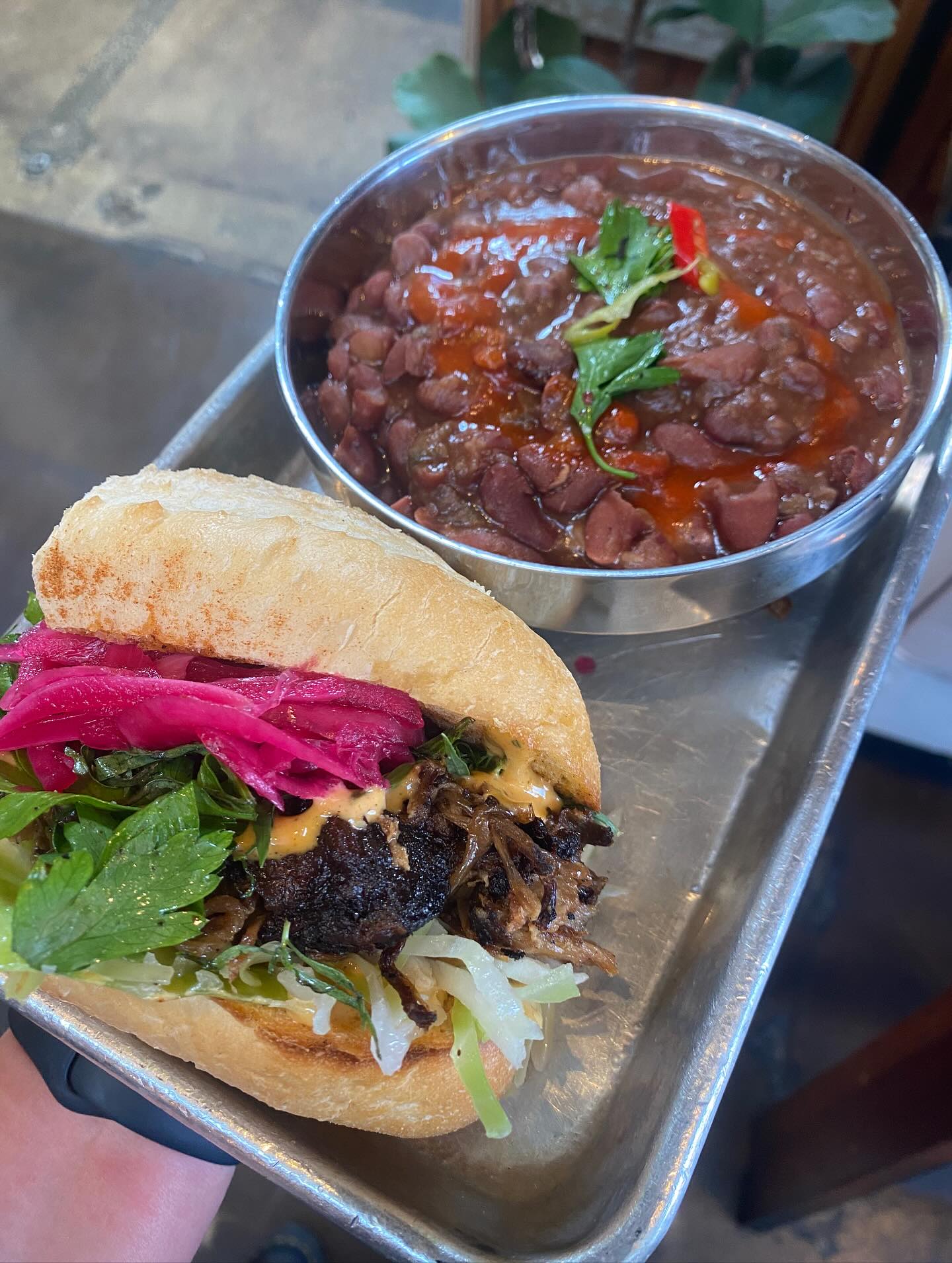 Sandwich with shredded meat, pickled onions, and red beans.