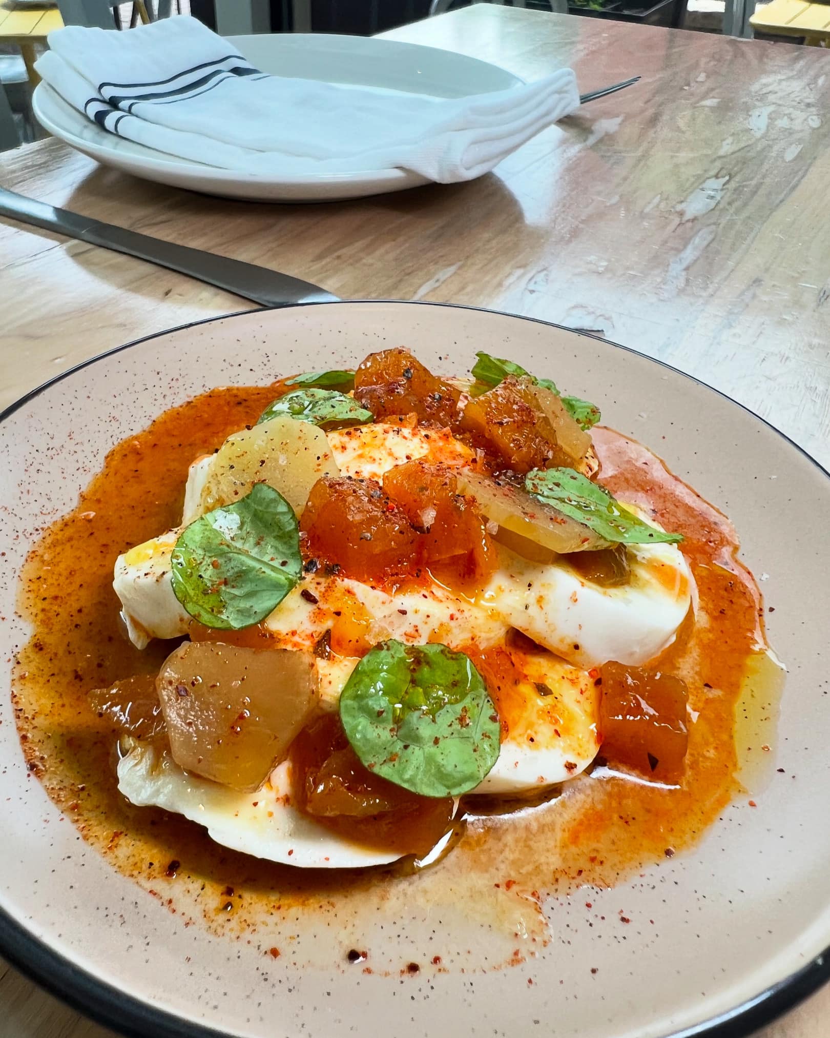 Plate with white mounds, orange chunks, green leaves, and reddish liquid.