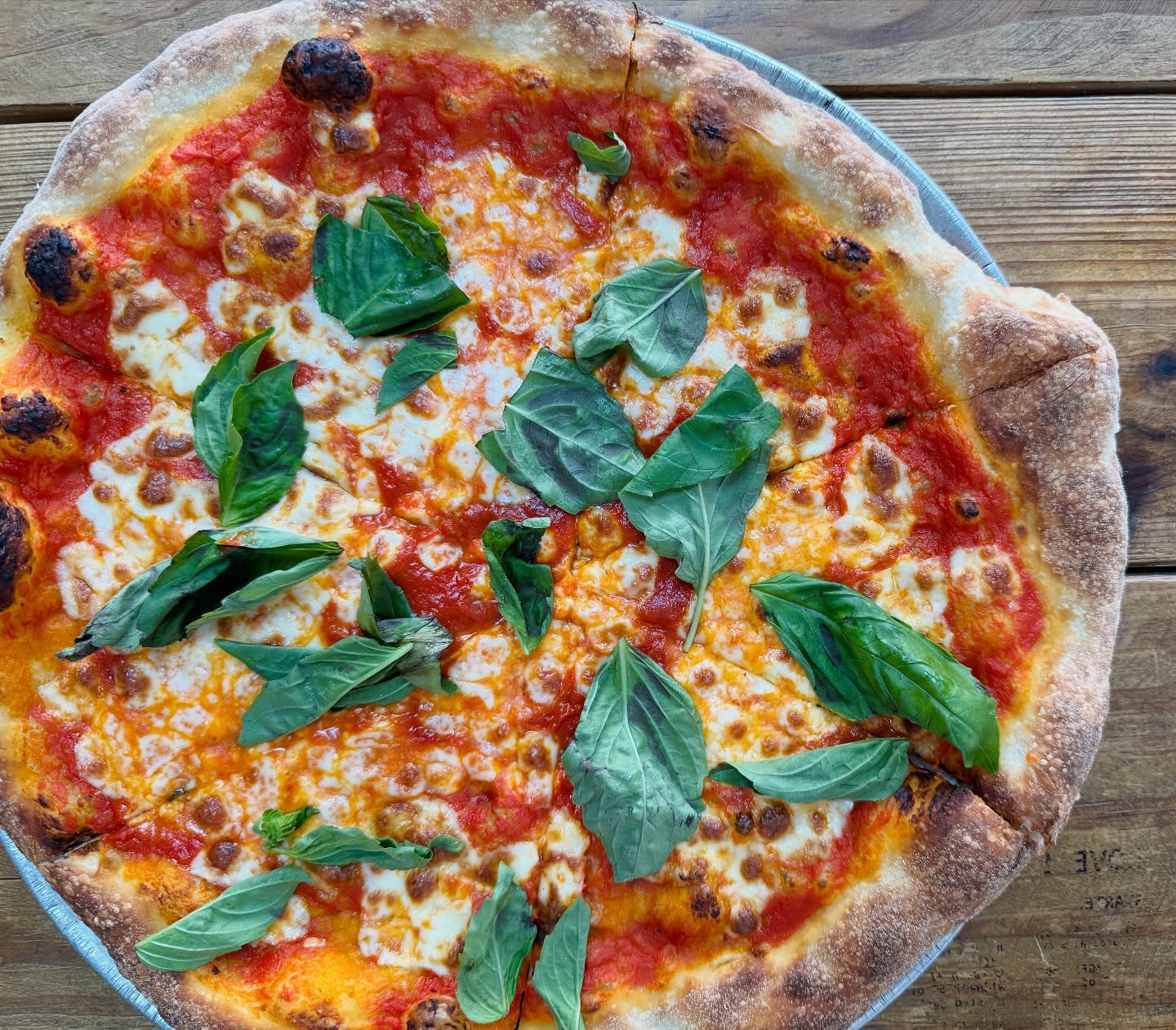 Whole pizza with tomato sauce, melted cheese, and fresh basil.