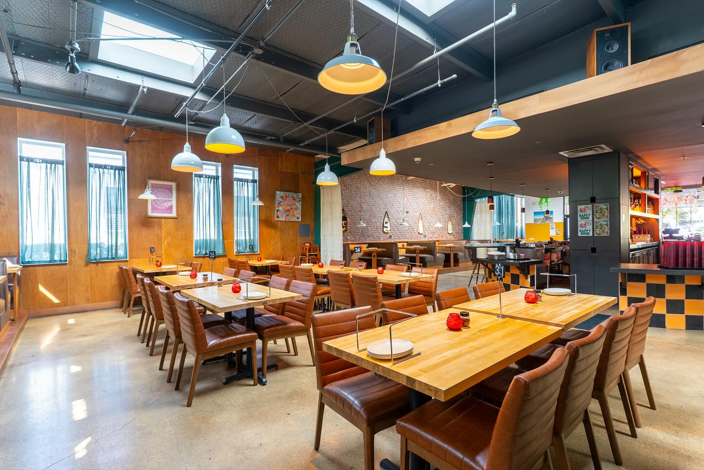 Empty, modern restaurant interior with wooden walls and industrial lighting.