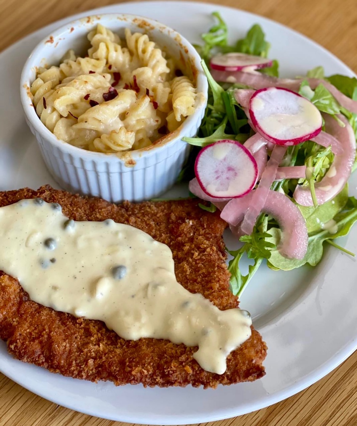 Breaded cutlet with caper sauce, baked pasta, and mixed green salad.
