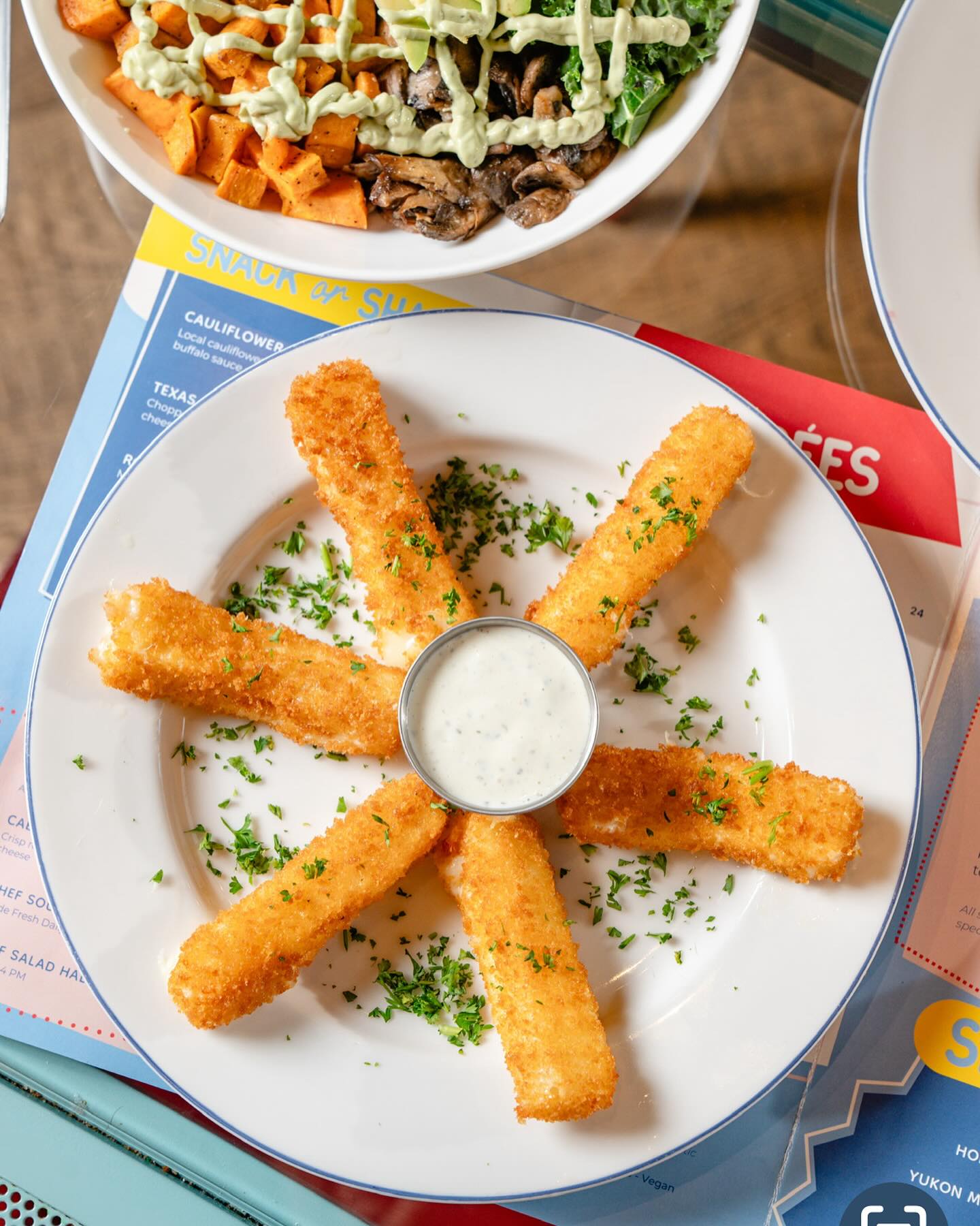 Fried golden cheese sticks with a side of white dipping sauce.