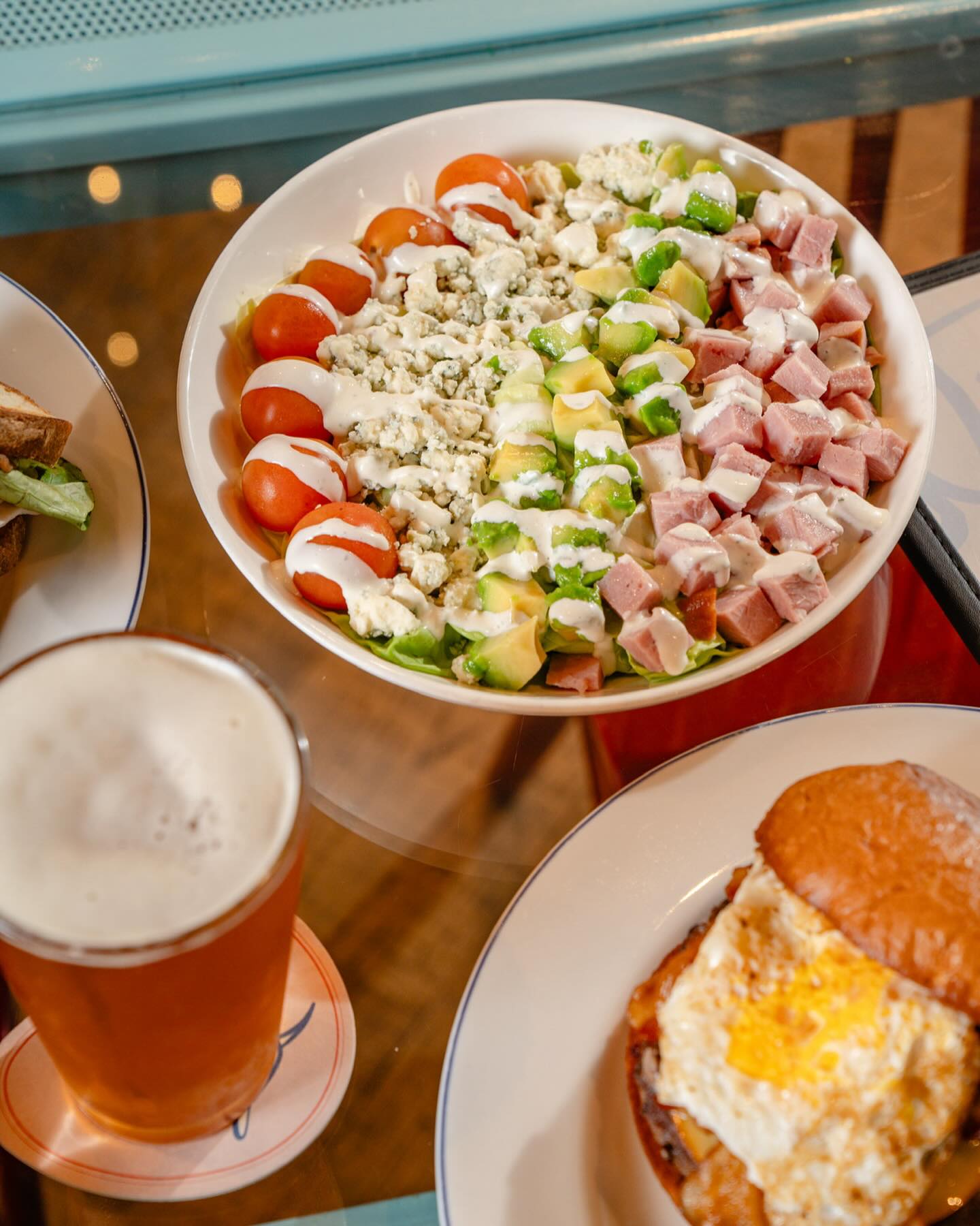 Cobb salad, burger with fried egg, and a glass of beer.