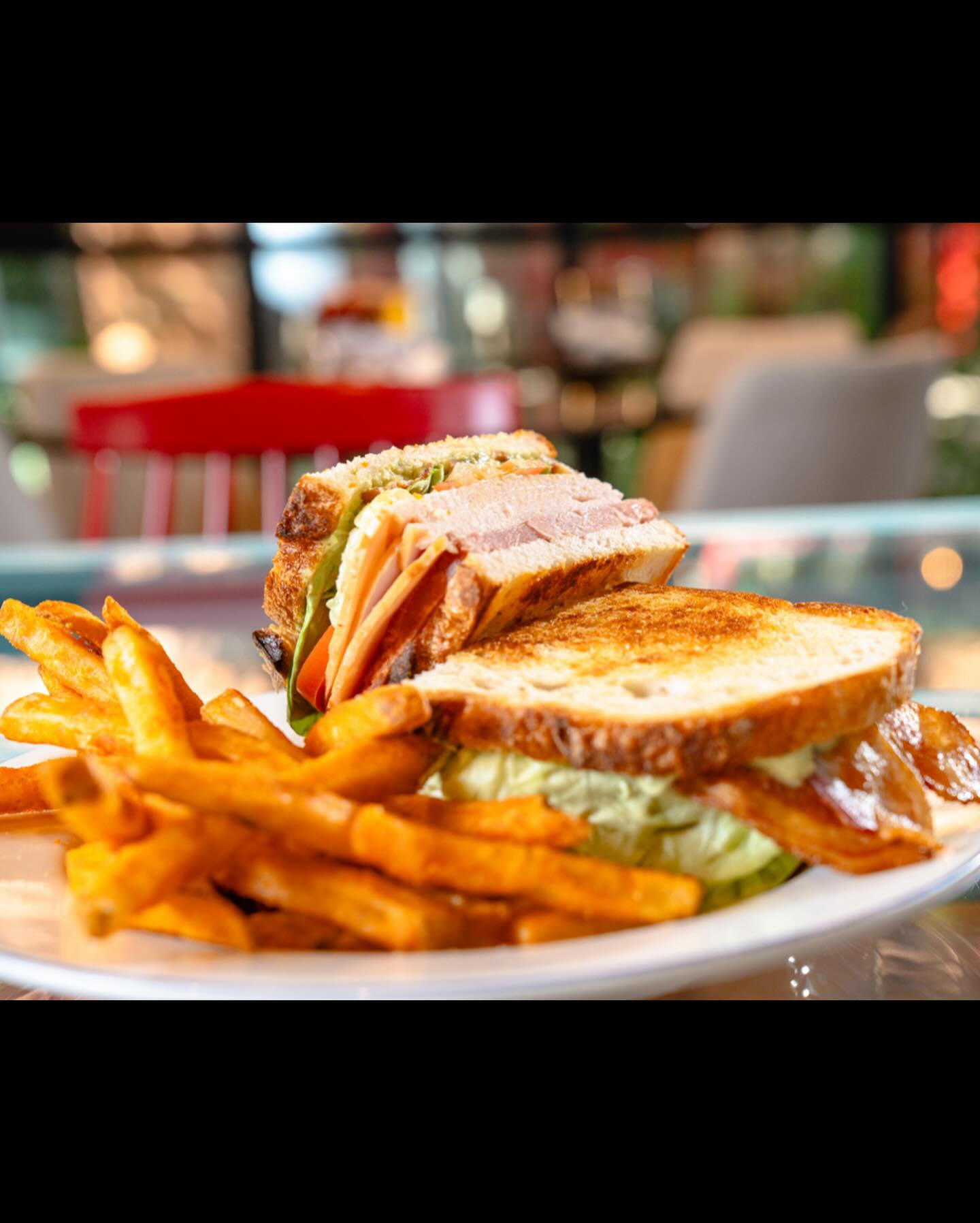 Club sandwich and fries on a plate in a restaurant setting.