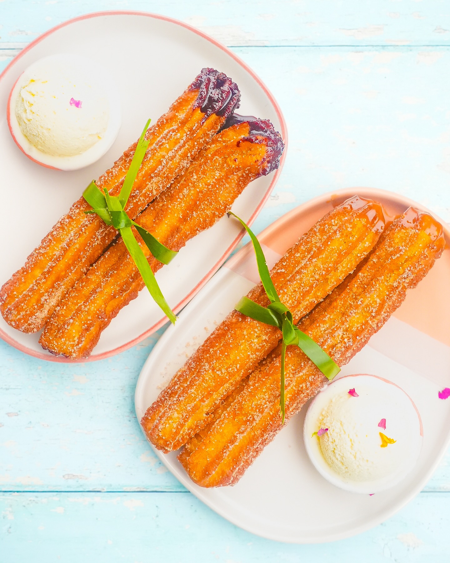 Two plates of sugared churros with ice cream and different toppings.