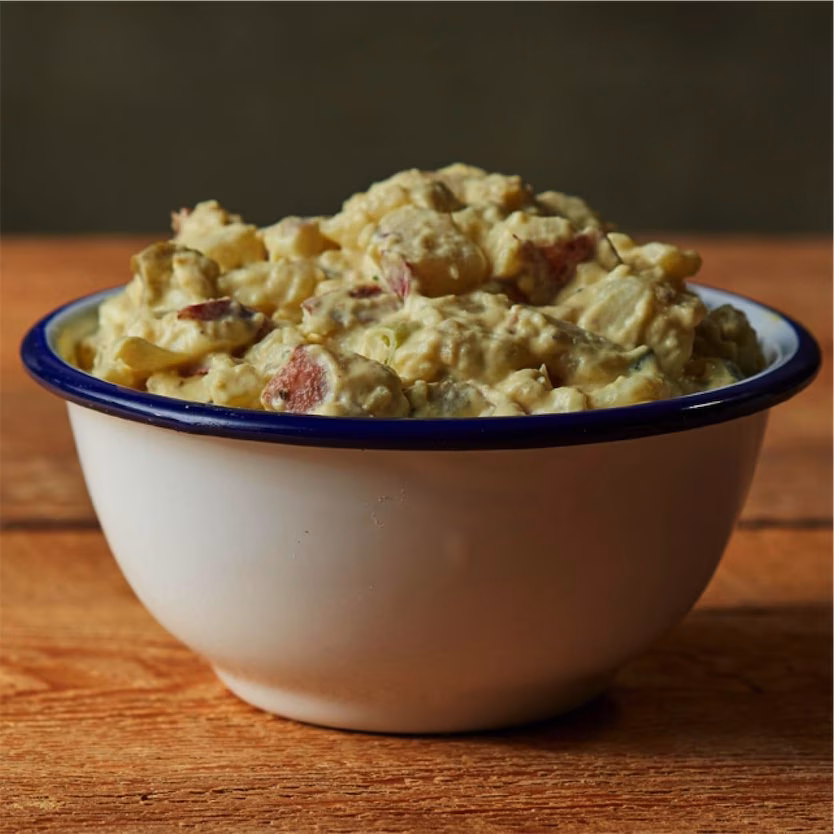 Creamy potato salad with red-skinned potatoes in a white bowl.