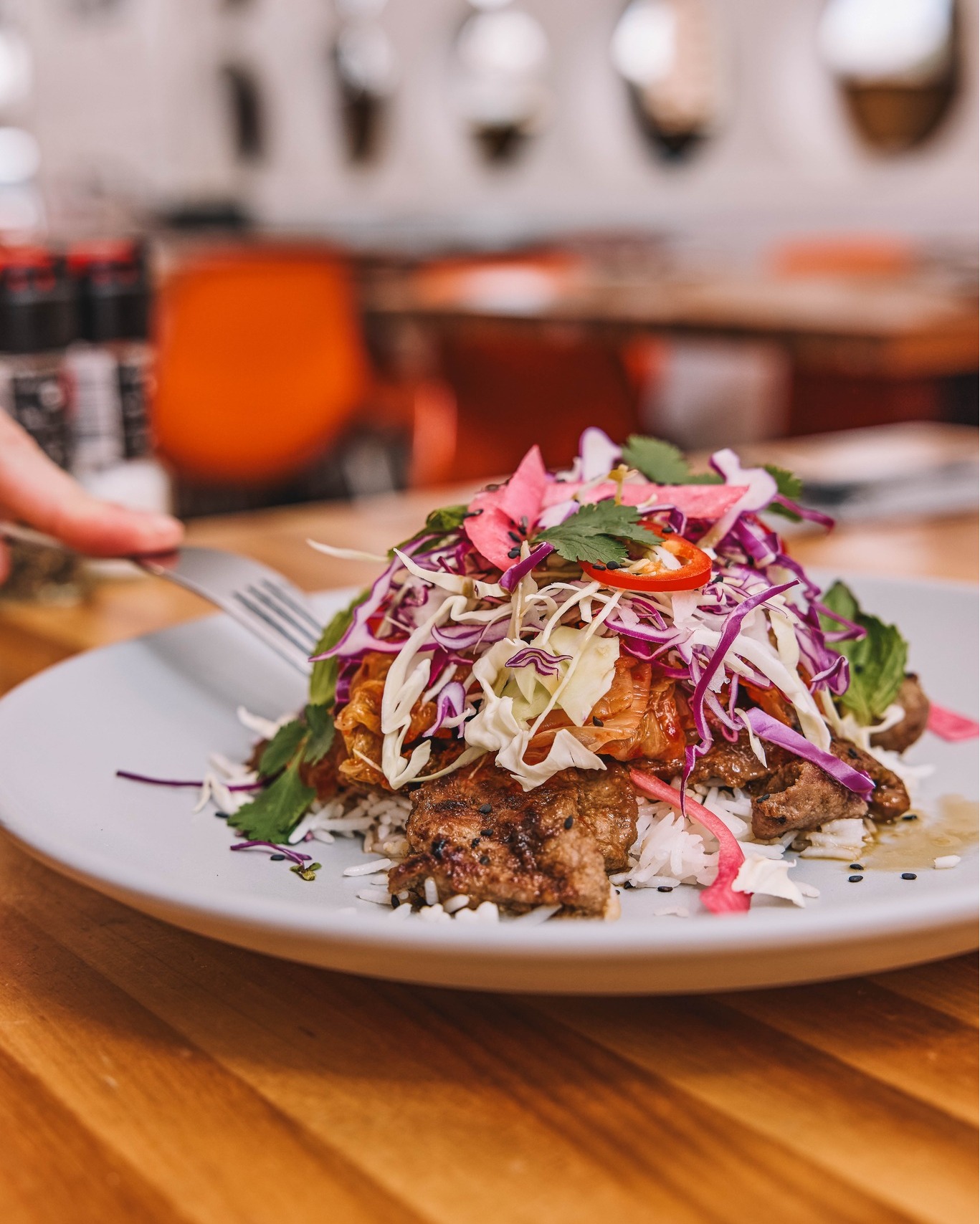 Grilled meat and rice topped with colorful cabbage and kimchi.