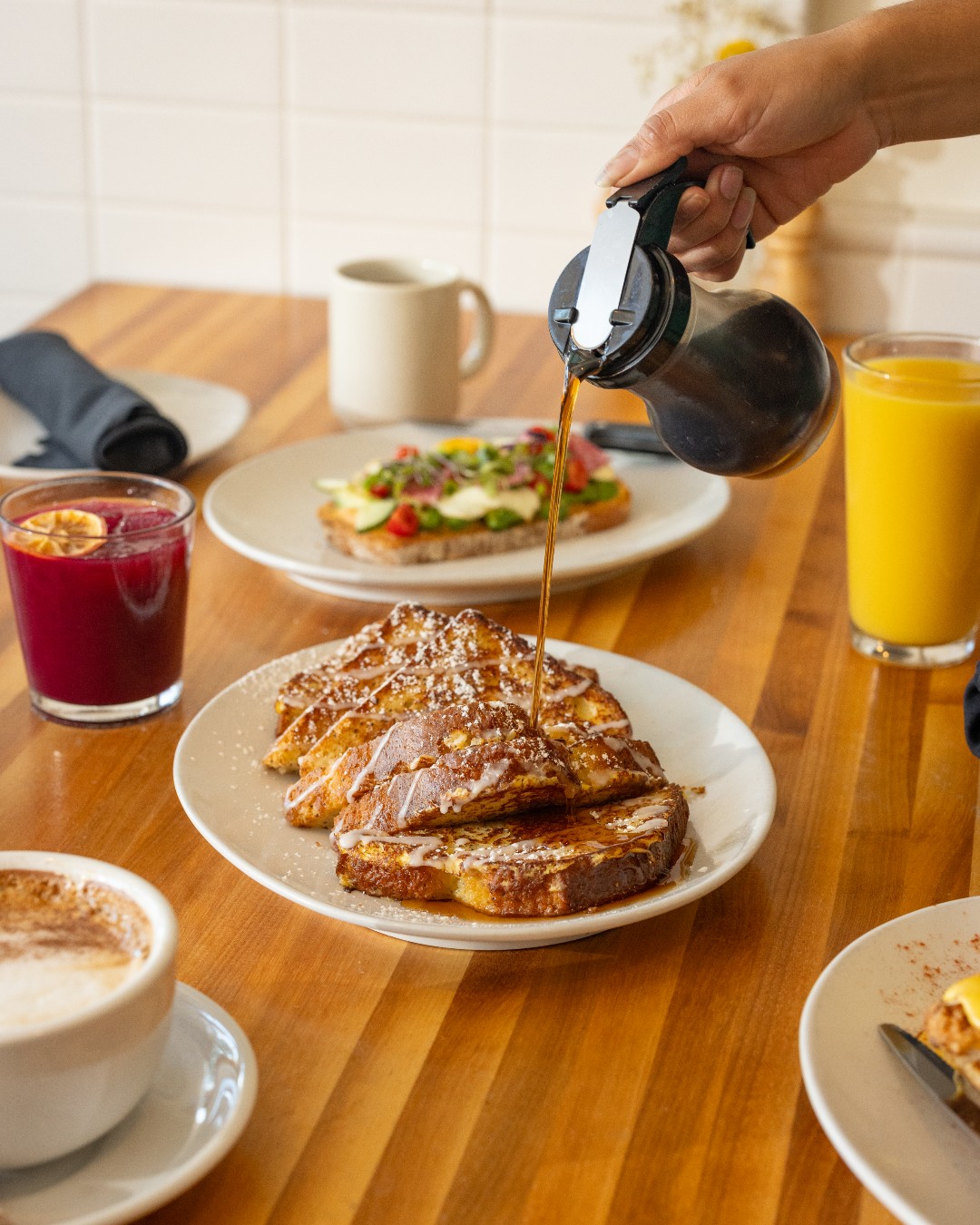 Close-up of syrup being poured on French toast with powdered sugar.