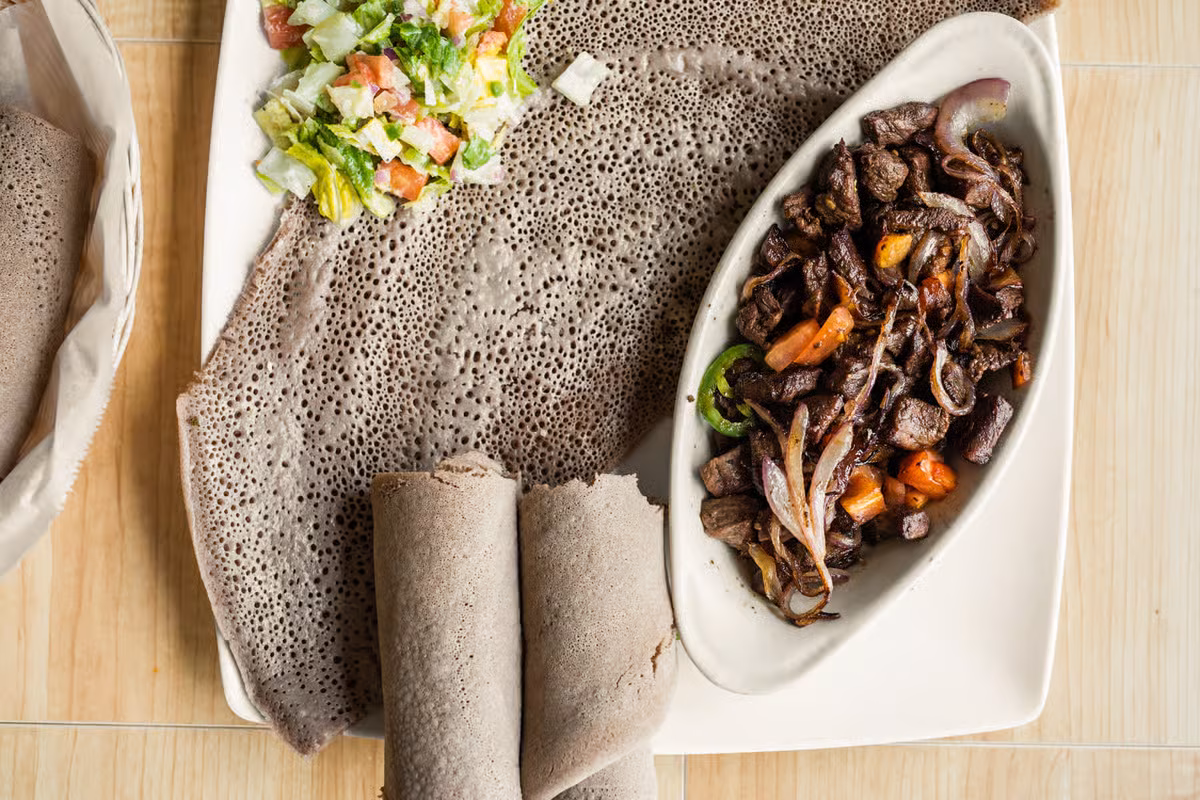 Ethiopian injera with a side salad and sautéed meat dish.