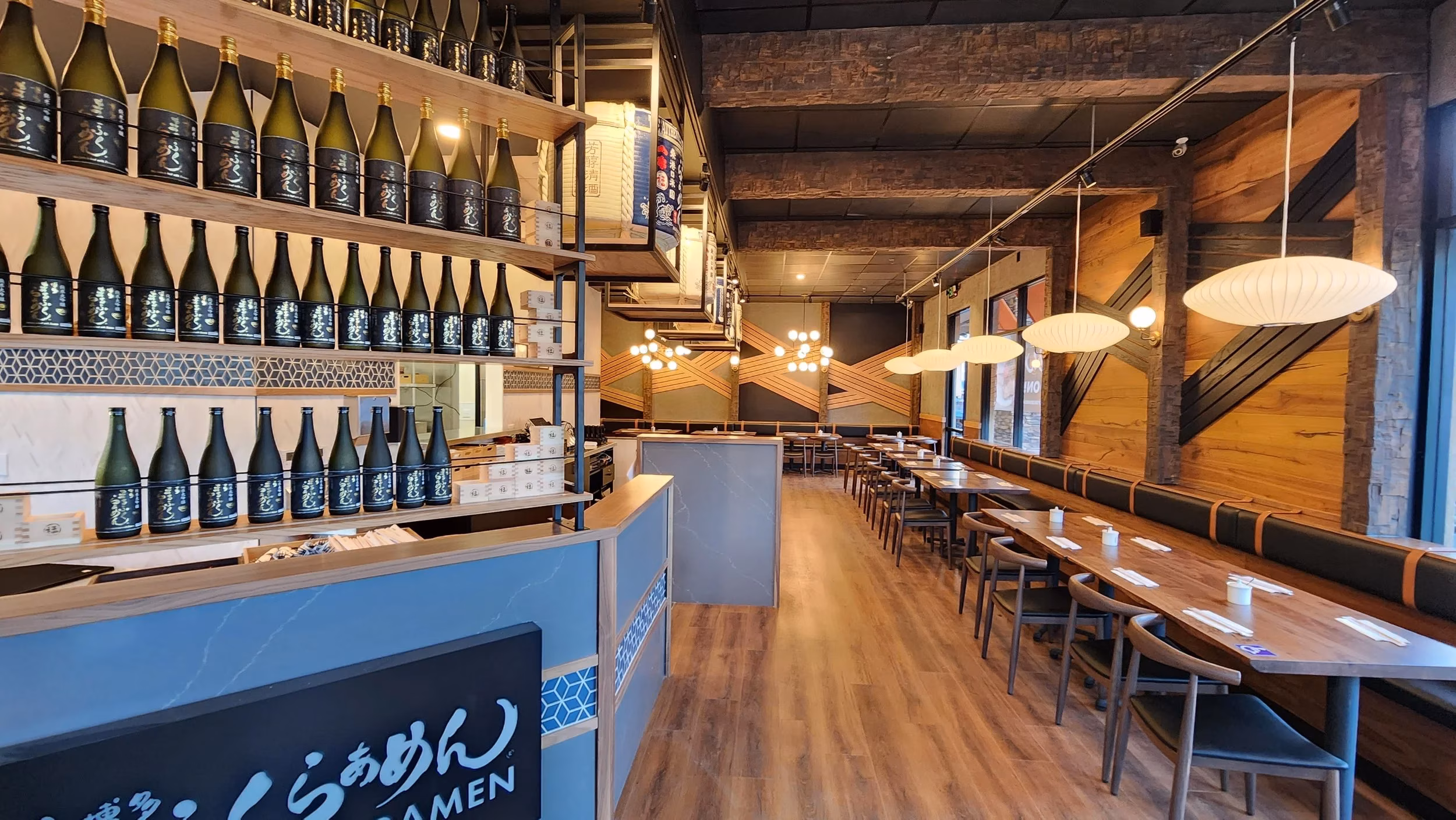 Interior of a modern Japanese restaurant with sake bottles and dining tables.
