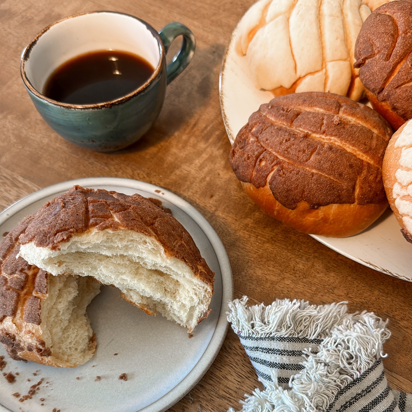 Mexican conchas and a cup of coffee on a wooden table.