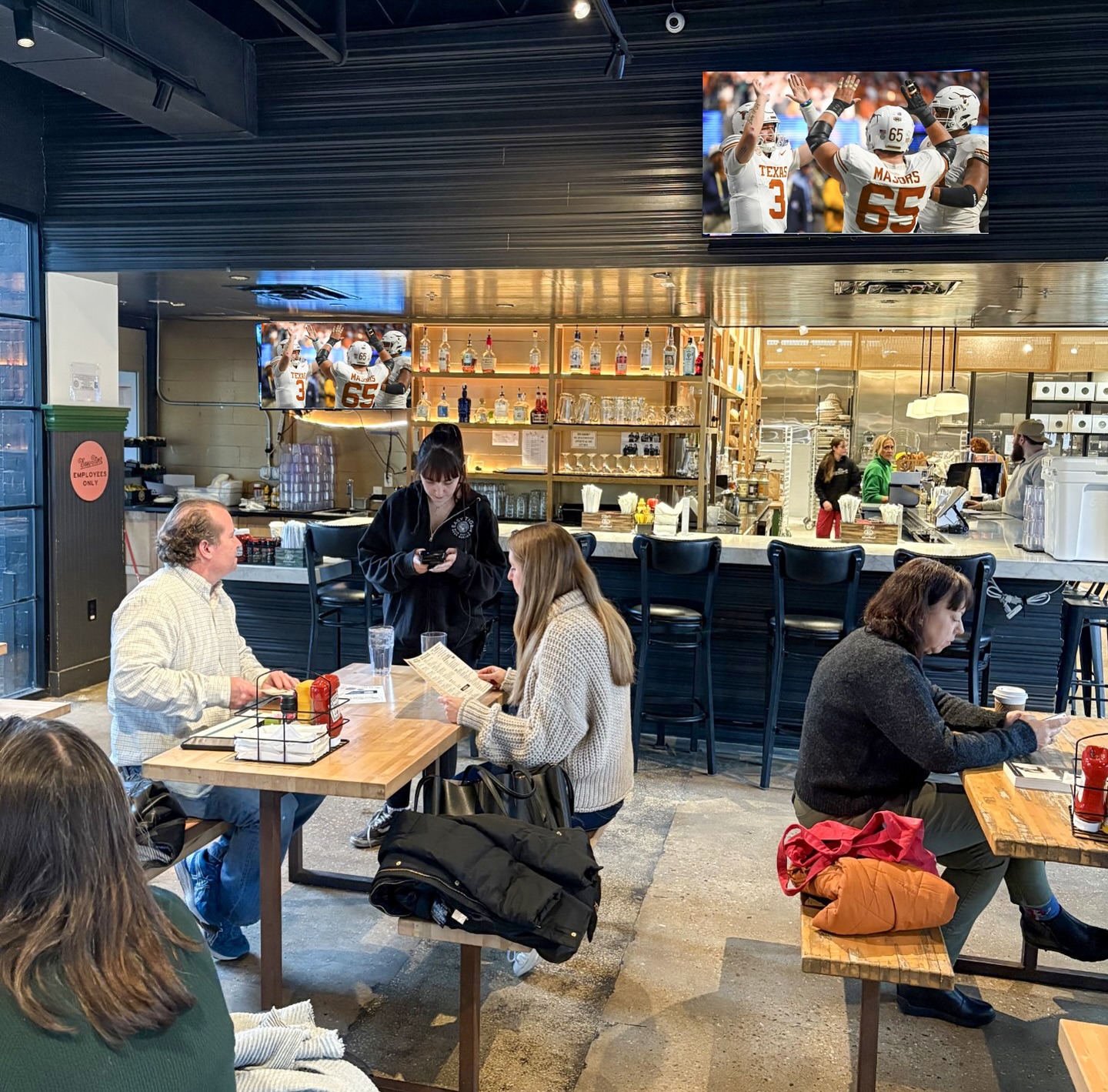 Restaurant with customers and screens showing a Texas Longhorns football game.