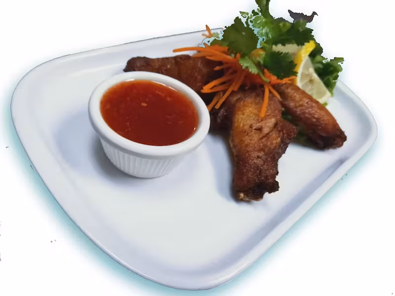 Fried chicken wings with red dipping sauce, carrots, cilantro, and lemon.