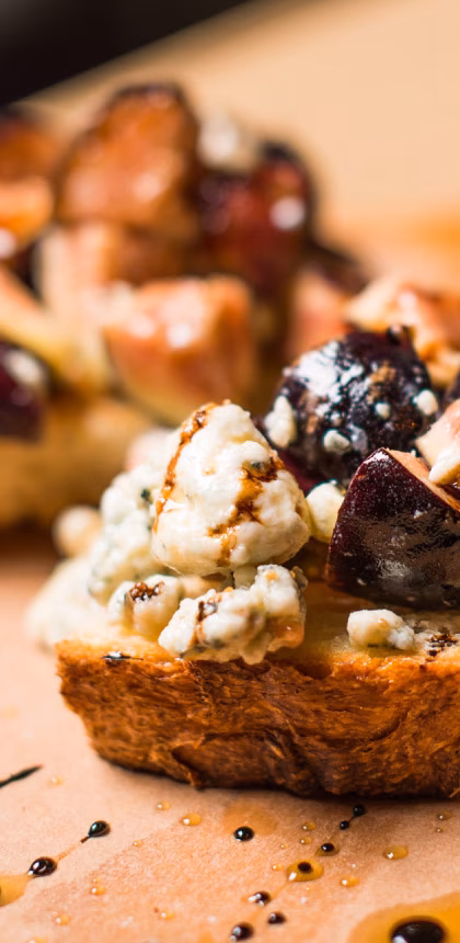 Close-up of bruschetta with blue cheese, figs, and balsamic glaze.