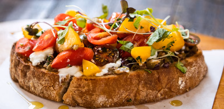 Bruschetta with colorful tomatoes, white cheese, and fresh green sprouts.