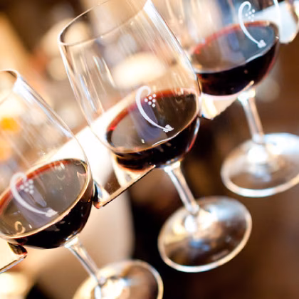 Multiple glasses of red wine with grape motif decorations.