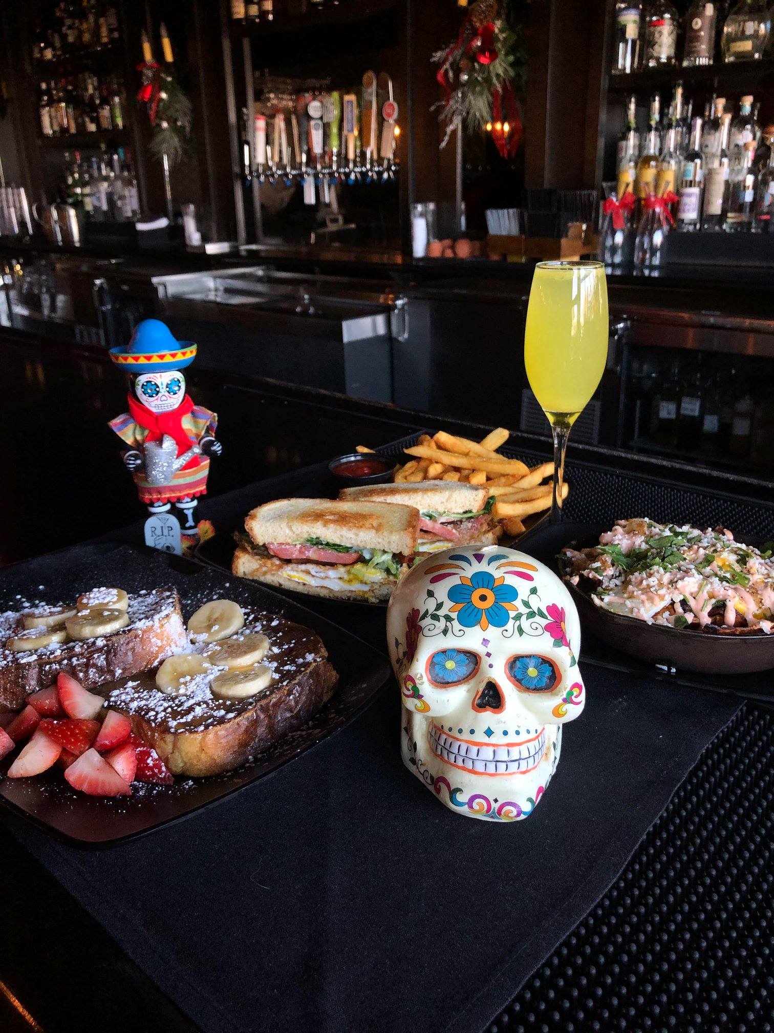Brunch items, yellow drink, and skull decorations at a bar.