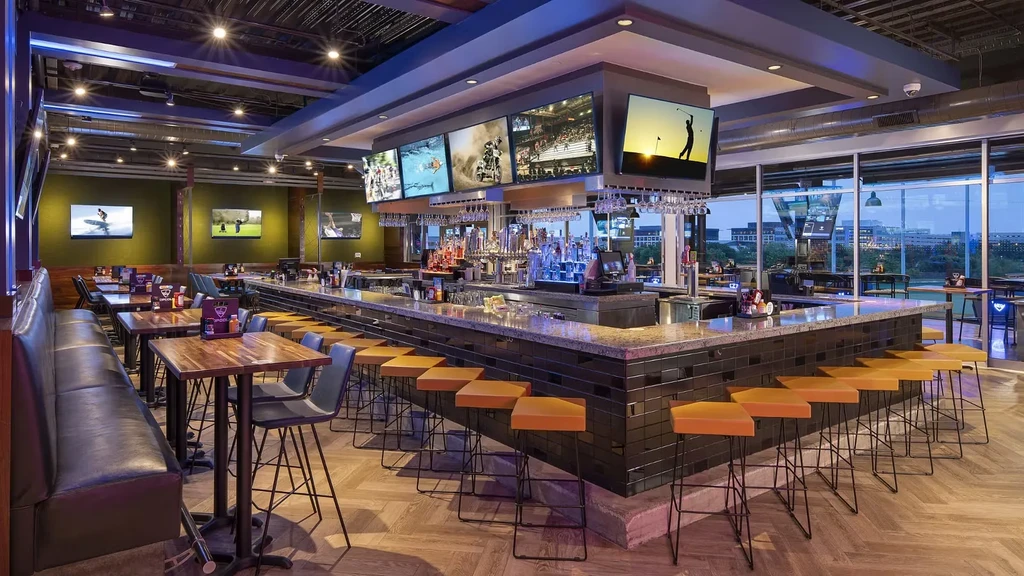 Modern restaurant bar with granite counter, sports TVs, and city view.